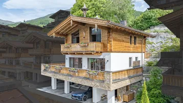 Traditionelles Holzchalet mit Balkonen und Carport in alpiner Umgebung.