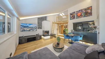 Moderner offener Wohn- und Essbereich mit Kamin, Holzboden und integrierter Küche.