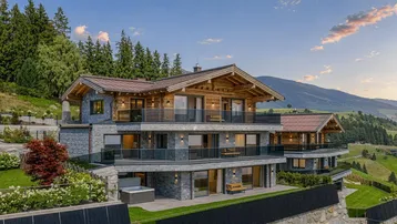 Luxuriöses Chalet mit moderner Architektur, Stein- und Holzfassade, umgeben von alpiner Landschaft.