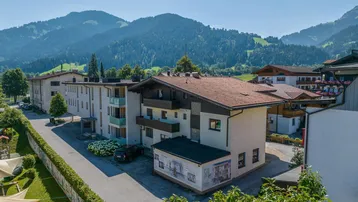 Gebäude in alpiner Umgebung mit Balkonen und Blick auf die Berge unter blauem Himmel.