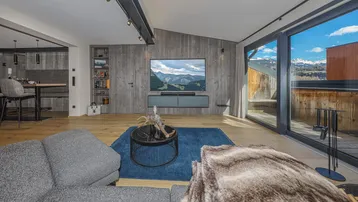 Modernes Wohnzimmer mit Holzwänden, Parkettboden und Zugang zu einem Balkon mit Bergblick.