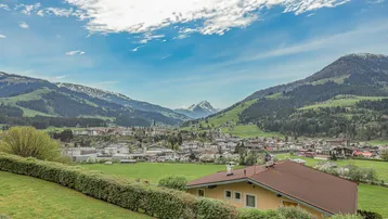 Panoramablick über ein malerisches Tal mit einem Dorf und majestätischen Bergen im Hintergrund.