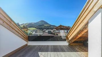 Sonniger Dachterrassenbereich mit Holzboden und weitem Blick auf die umliegende Berglandschaft.