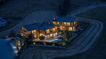Luxuriöse Chalets in alpiner Umgebung bei Nacht mit beleuchtetem Außenbereich und Pool.