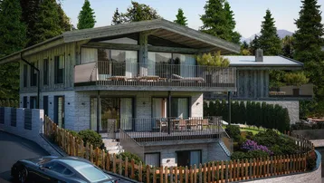 Modernes Haus mit Holz- und Steinfassade, mehreren Balkonen und Terrassen in alpiner Umgebung.
