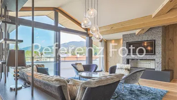 Helles Wohnzimmer mit großen Panoramafenstern, Bergblick, modernem Kamin und Holzbalken.
