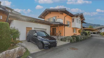 Traditionelles Haus im Alpenstil mit Holzdetails, gepflasterter Auffahrt und Bergblick.