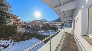 Sonniger Balkon mit Glasgeländer und weitem Blick auf die Berglandschaft.