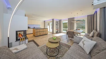 Modernes offenes Wohnzimmer mit Kamin, Essbereich und integrierter Küche, hell und geräumig.