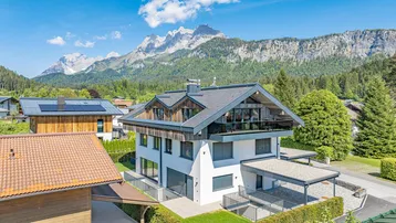 Modernes Einfamilienhaus mit Holzfassade und Bergblick in alpiner Umgebung.
