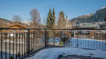 Balkon mit Schnee und Blick auf die verschneite Berglandschaft und das Dorf.