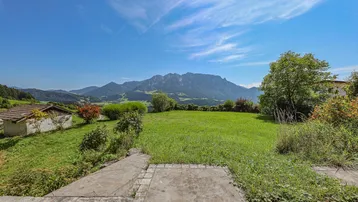 Weitläufiger Gartenbereich mit grüner Wiese und beeindruckendem Panoramablick auf die umliegenden Berge.
