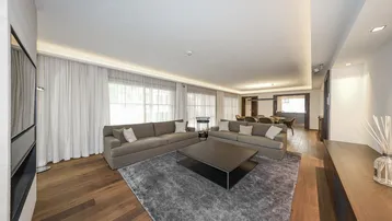 Geräumiger, offener Wohn- und Essbereich mit bequemen Sofas, Holzboden und großen Fenstern.
