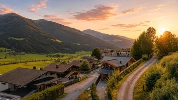 Malerische Berglandschaft bei Sonnenuntergang mit traditionellen Häusern und grünen Tälern.