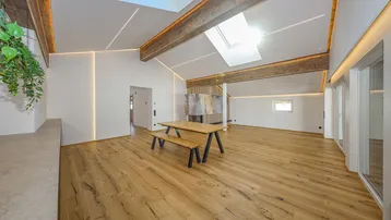Helles, offenes Wohnzimmer mit Holzbalken, Dachfenstern und modernem Kamin.