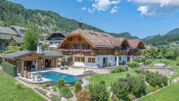 Großzügiges Anwesen mit traditionellem Haus, Pool, Whirlpool und gepflegtem Garten in alpiner Landschaft.