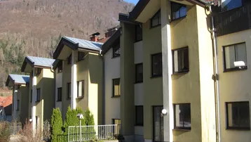 Mehrere Reihenhäuser in einer bergigen Landschaft mit sonnigem Wetter und grüner Umgebung.