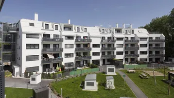 Moderne Wohnanlage mit mehreren Gebäuden, Balkonen und einem gemeinschaftlichen Grünbereich mit Spielplatz.