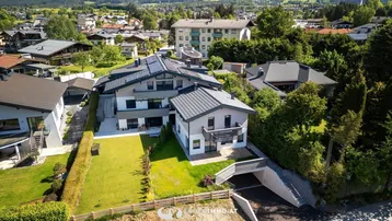 Luftaufnahme eines modernen Wohnkomplexes mit gepflegten Gärten und umliegender Bebauung.