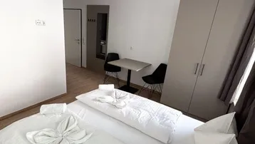 Helles Schlafzimmer mit Doppelbett, Kleiderschrank und kleinem Esstisch für zwei Personen.