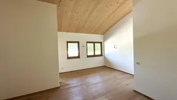 Heller, unmöblierter Raum mit Holzbalkendecke und Parkettboden, bereit für individuelle Gestaltung.