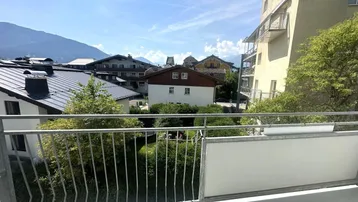 Balkon mit weitem Blick über Dächer, Häuser und die umliegende Berglandschaft.