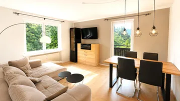 Helles Wohn- und Esszimmer mit Holzboden, beigem Sofa und modernem Esstisch.