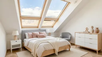 Helles Schlafzimmer im Dachgeschoss mit großen Dachfenstern und modernem Interieur.
