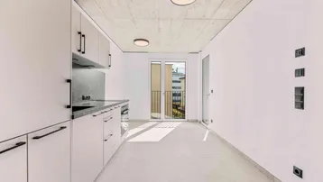 Moderne Einbauküche mit hellen Fronten, Fliesenboden und Zugang zu einem französischen Balkon.