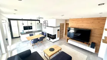 Moderner offener Wohn- und Essbereich mit integrierter Küche, Kamin und Holzakzenten.