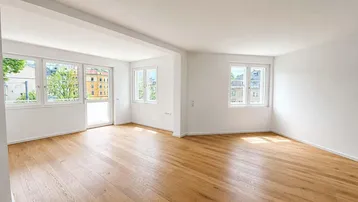 Helles und geräumiges Wohnzimmer mit neuem Parkettboden und Zugang zum Balkon.