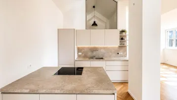 Moderne Küche mit Kücheninsel, Induktionskochfeld und hohen Decken in einem hellen Raum.