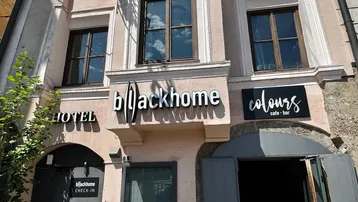 Historisches Gebäude mit Hotel- und Café-Bar-Schildern an der Fassade in einer städtischen Umgebung.