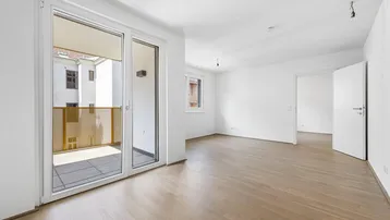 Helles Zimmer mit Parkettboden und Zugang zu einem sonnigen Balkon.