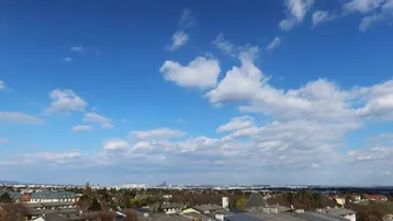 Weitläufiger Blick über die Stadt und die umliegende Landschaft unter blauem Himmel.