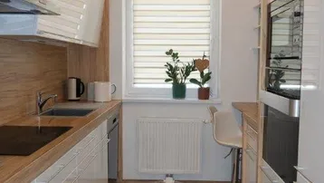 Moderne, helle Küche mit weißen Hochglanzfronten, Holzarbeitsplatte und integrierten Geräten.