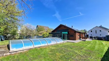 Großer Garten mit Holzhaus, überdachtem Pool und sonniger Terrasse.