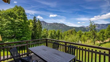 Geräumiger Holzbalkon mit Esstisch und Stühlen, bietet einen atemberaubenden Bergblick.