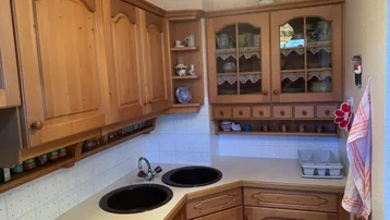 Traditionelle Holzküche mit vielen Schränken, dunklen Spülbecken und gefliestem Spritzschutz.