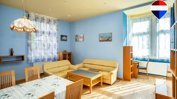 Helles Wohn- und Esszimmer mit blauen Wänden, gelber Decke und Holzboden.