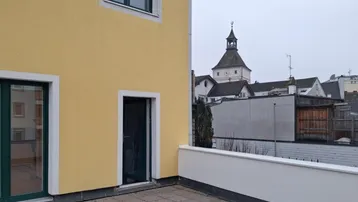 Geräumige Terrasse mit Blick auf die Stadt und einen historischen Turm.