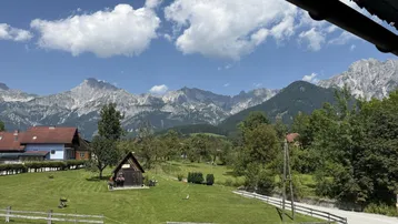 Panoramablick auf die majestätischen Berge und grüne Wiesen unter blauem Himmel an einem sonnigen Tag.
