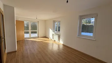 Helles Wohnzimmer mit Laminatboden und Zugang zum verschneiten Außenbereich.