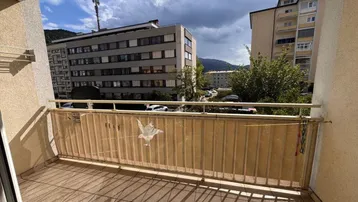Geräumiger Balkon mit Fliesenboden und Blick auf die umliegenden Gebäude und Grünflächen.