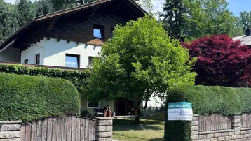 Traditionelles Haus mit Satteldach, umgeben von üppigem Grün und einem gepflegten Vorgarten.