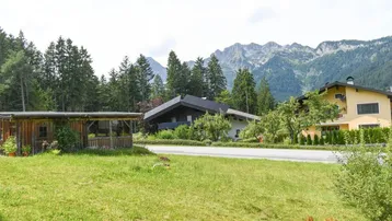 Weitläufige Grünfläche mit Blick auf umliegende Häuser und die majestätische Berglandschaft.