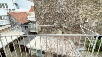 Balkon mit Blick auf einen begrünten Innenhof und umliegende Gebäude.