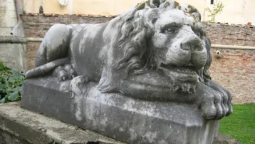 Alte steinerne Löwenstatue als dekoratives Element im Außenbereich des historischen Anwesens.