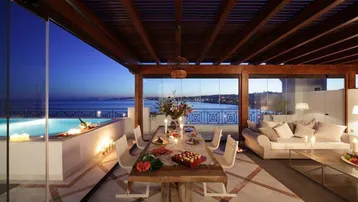 Luxuriöse Terrasse mit Essbereich, Lounge und Infinity-Pool, bietet einen atemberaubenden Meerblick bei Sonnenuntergang.
