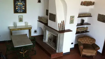 Gemütlicher Wohnbereich mit Kamin, Terrakottaboden und dekorativen Wandregalen.